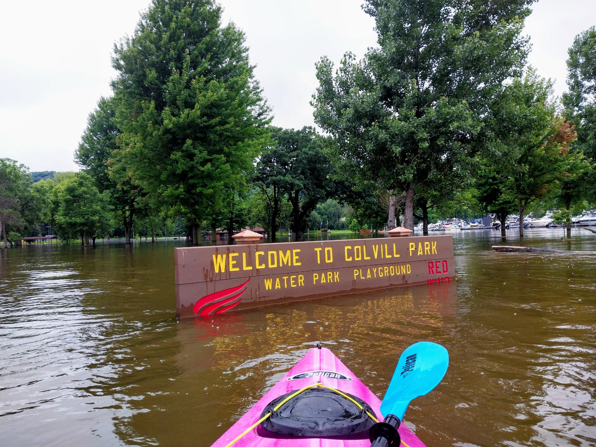 Paddling past a partly submerged Welcome to Colvill Park sign during high water